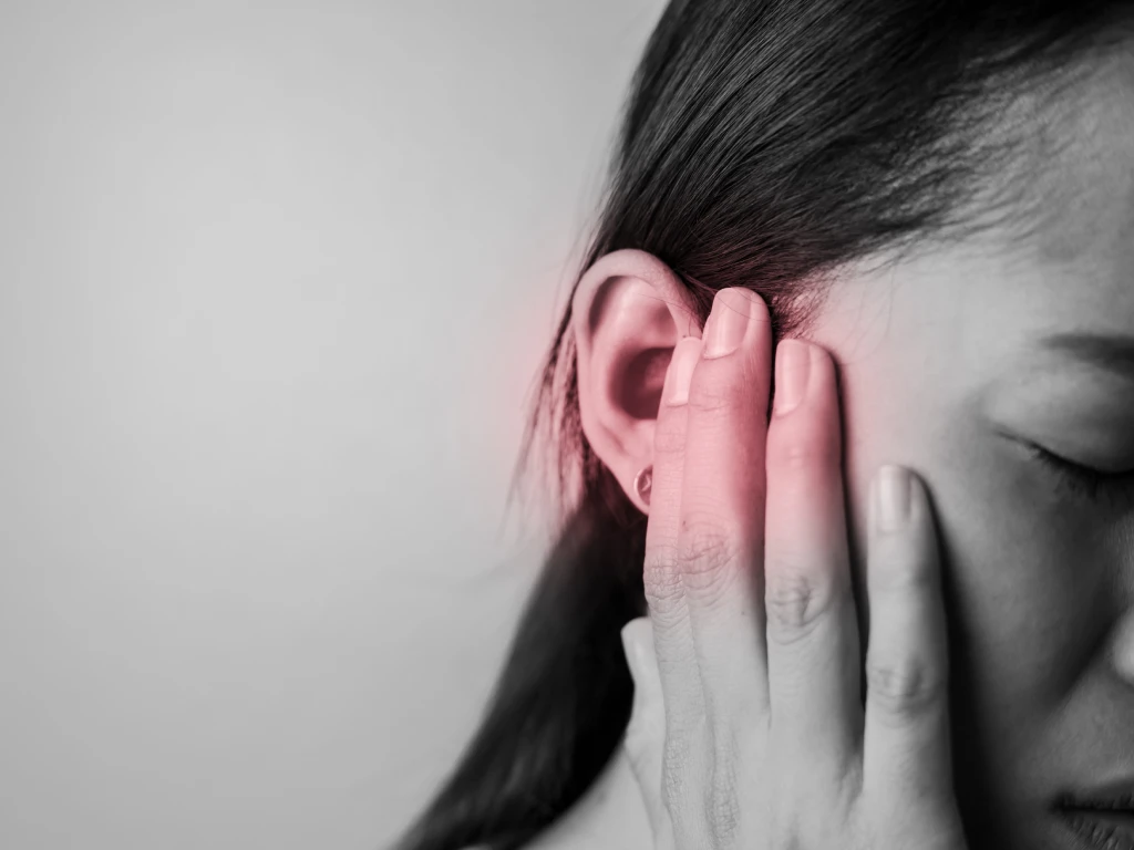 Woman holding painful ear from loud noise.