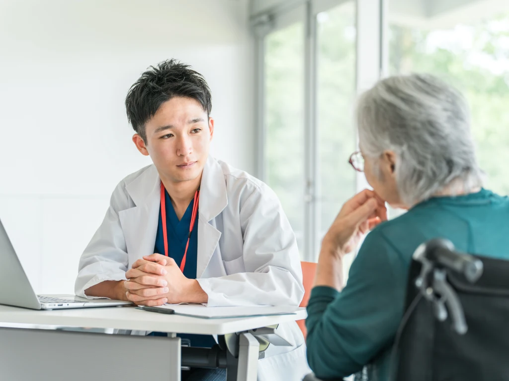 Dokter berdiskusi mengenai perawatan dokter spesialis dengan pasien lanjut usia